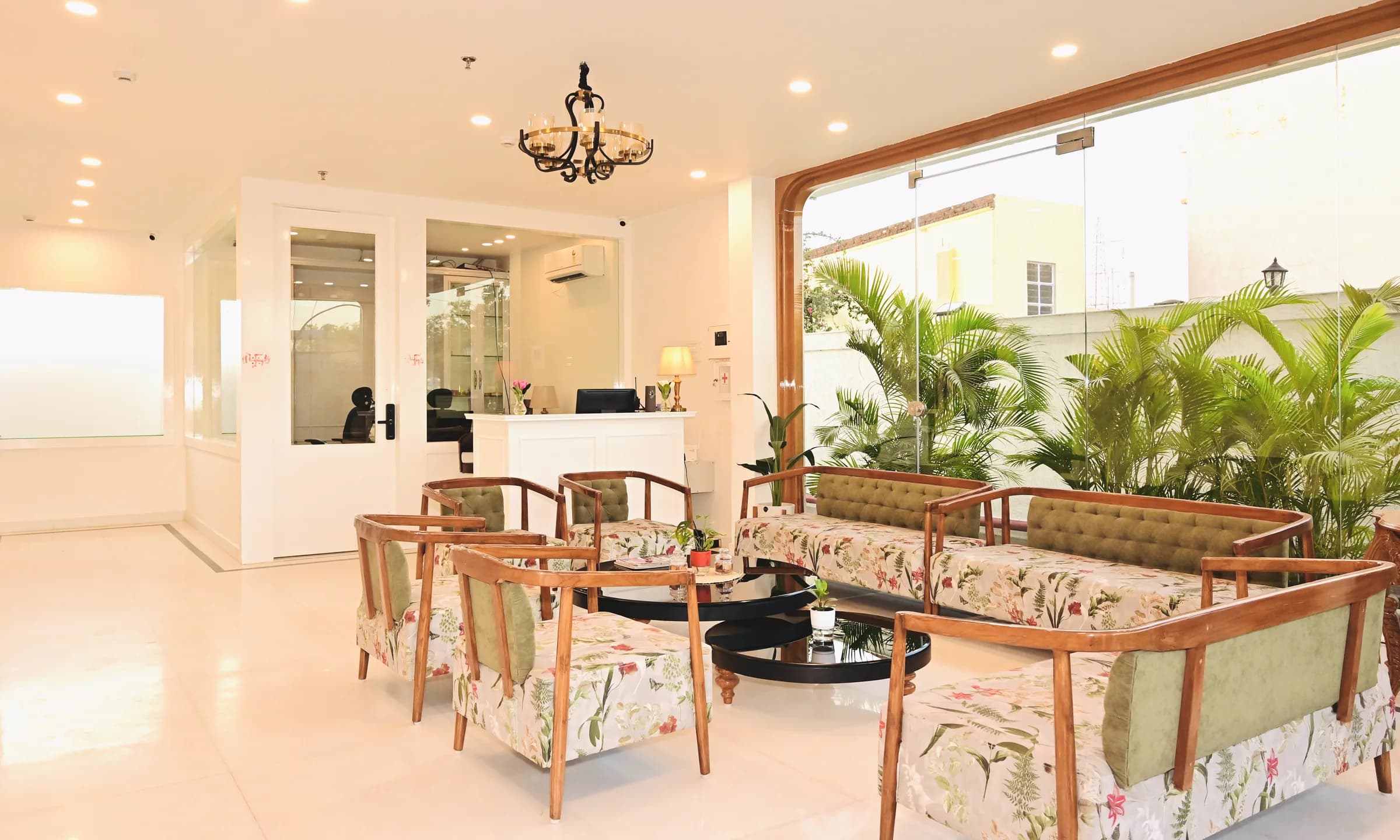 The reception of The Mohua, with a glass frontage, chandelier, palms and floral seating