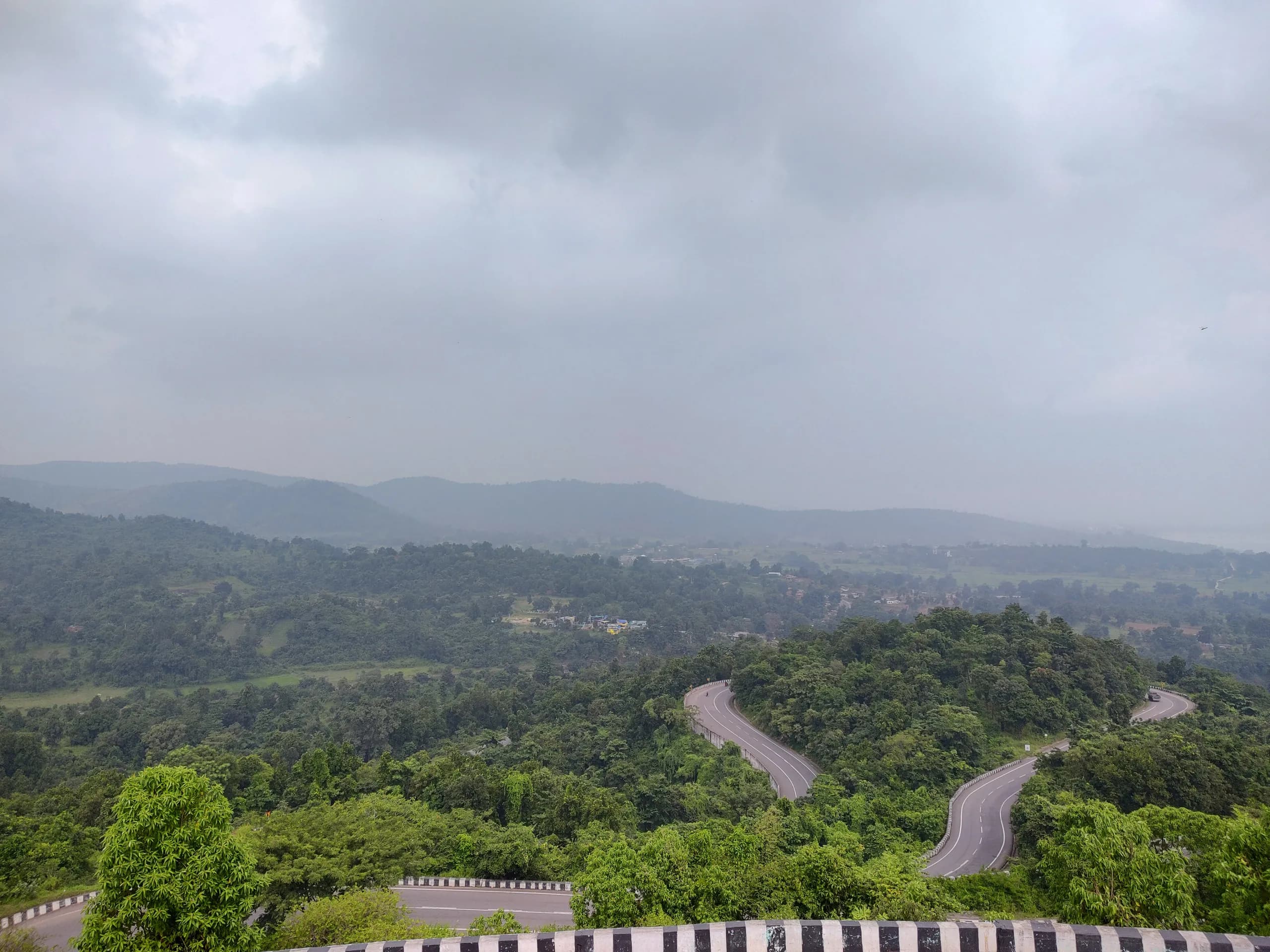 Hairpin bends winding through the green hills of Patratu Valley beneath a cloudy sky